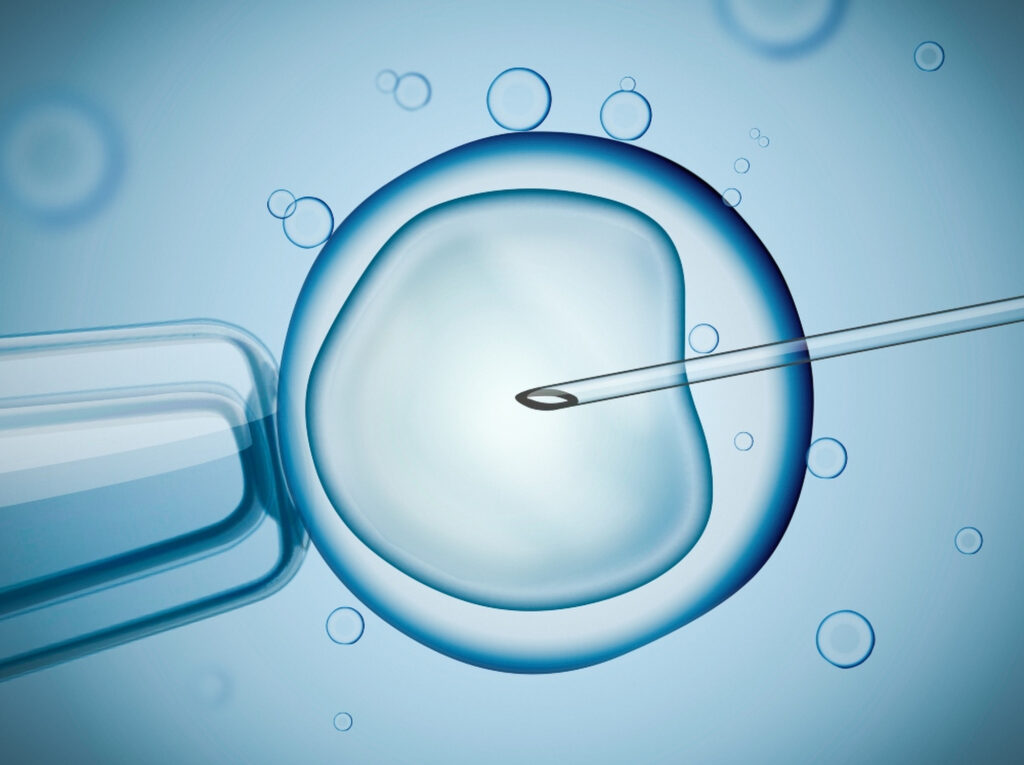 Needle injects large cell surrounded by fluid bubbles; blue tone suggests fertilization concept.